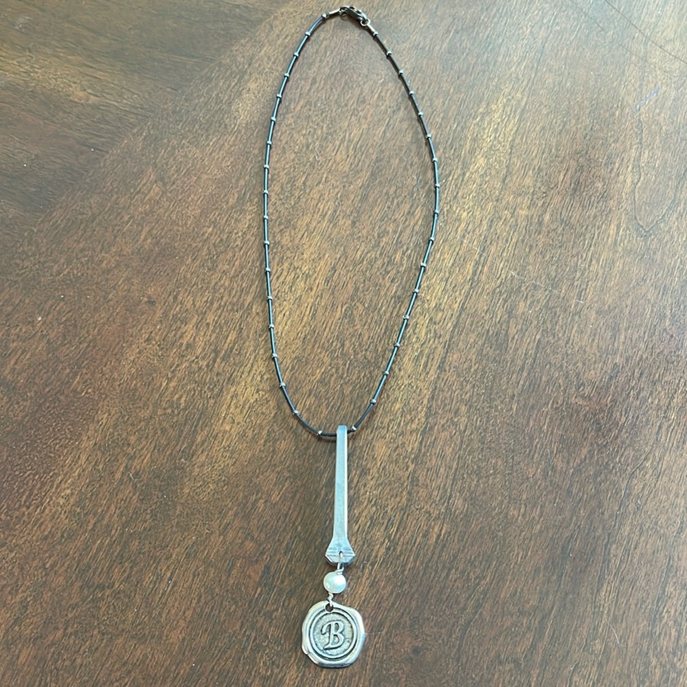 Black necklace with a “B” initial. Made by local artisan.